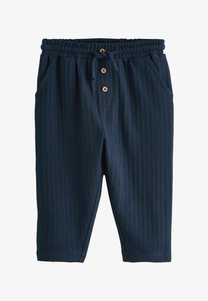 Marineblaue Hose mit strukturiertem, geripptem Design. Verfügt über einen elastischen Bund mit Kordelzug und drei Holzknöpfen. Mit seitlichen Taschen ausgestattet.