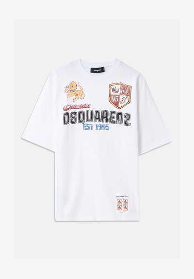 T-shirt en coton blanc avec des graphiques colorés, incluant un lion, des boucliers et du texte. Coupe décontractée avec des manches courtes. Accents en rouge et bleu.