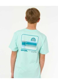 Camiseta de algodón verde menta con un estampado gráfico de olas estilizadas del océano y un sol, con el texto "RIPCURL" en azul.