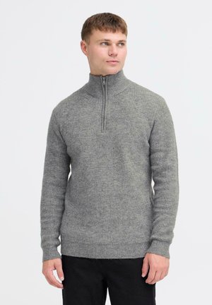Pull en tricot gris clair avec un col montant et une fermeture éclair quart de zip ; présente un motif texturé et des poignets et un ourlet côtelés.