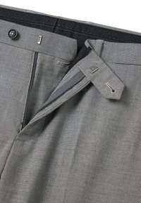 Grijze broek met een ritssluiting, stoffen label en zijzakken, gemaakt van een getextureerd materiaal met een subtiel visgraatmotief.