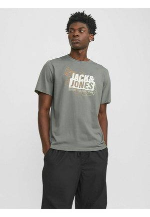 Camiseta de algodón gris con un estampado gráfico que incluye el texto "JACK & JONES" en blanco y amarillo, combinada con pantalones cortos negros.