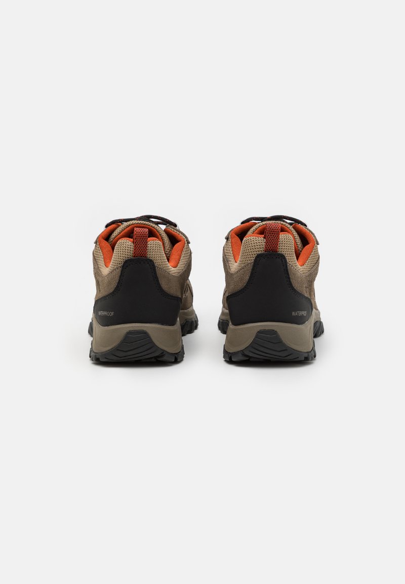 Zapatillas de senderismo impermeables marrones con acentos negros, paneles de malla y detalles naranjas; talón definido y suela de goma texturizada.