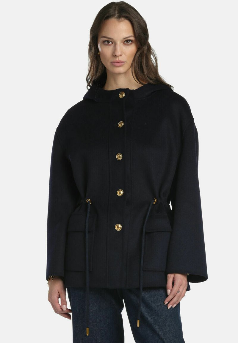 Giacca navy con cappuccio, bottoni dorati, coulisse in vita e due tasche frontali; presenta un tessuto morbido e strutturato e una vestibilità comoda.