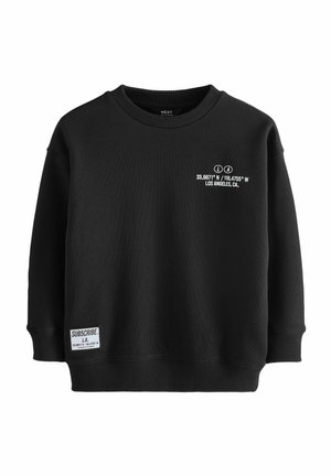 Zwarte sweater met een ronde halslijn, verlaagde schoudernaden en geribbelde manchetten. Heeft witte tekst en een label op de voorkant. Zachte textuur.