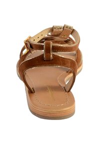 Sandalo in suede marrone con suola piatta, cinturino alla caviglia e dettagli metallici. Design con punta aperta, caratterizzato da dettagli cuciti e plantare beige.