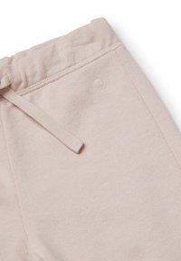 Světle růžové bavlněné tepláky mají elastický pas se šňůrkou a malým vyšívaným logem na boku. Jemná textura a bezešvý design.