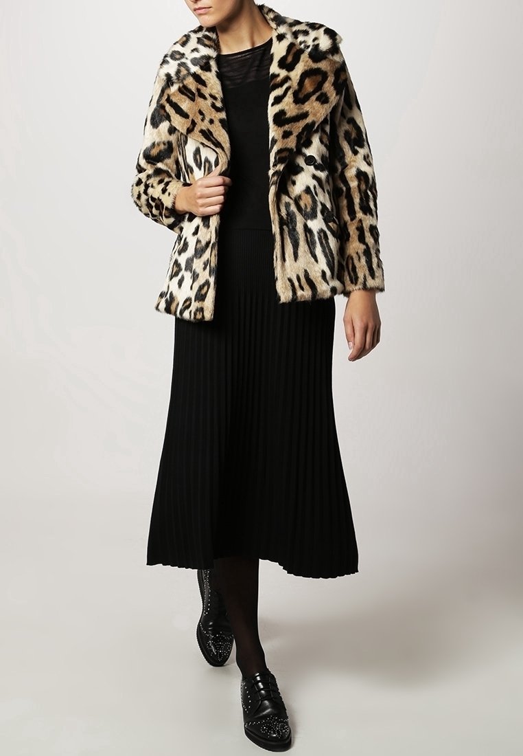 Leopardprint nepsja met een sjawl-achtige kraag; gecombineerd met een zwarte geribde lange rok en zwarte nagelstudschoenen.