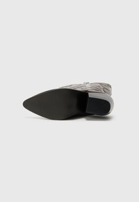 Bottines en cuir avec un motif texturé matelassé en gris clair. Présentent un bout pointu et une semelle en caoutchouc noire.