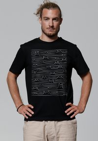 Schwarzes Baumwoll-T-Shirt mit einer weißen Linienzeichnung von Katzen und abstrakten Wellen auf der Vorderseite. Kurze Ärmel und ein Rundhalsausschnitt.