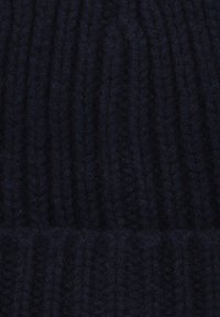 Zbliżenie na ciemnoniebieską, prążkowaną dzianinę o miękkiej, puszystej teksturze i pionowych wzorach.