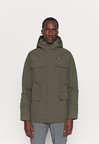 Olive green parka jacket made of durable material, featuring a hood, multiple front pockets, and a zip closure. Plain texture, minimal design.