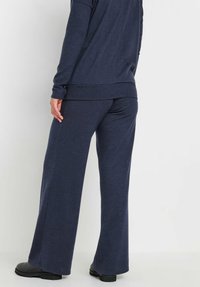 Navy blauwe, zachte stoffen loungewear set met een lange mouwen top en brede broekspijpen met een ontspannen pasvorm. Gelaagd, casual ontwerp.