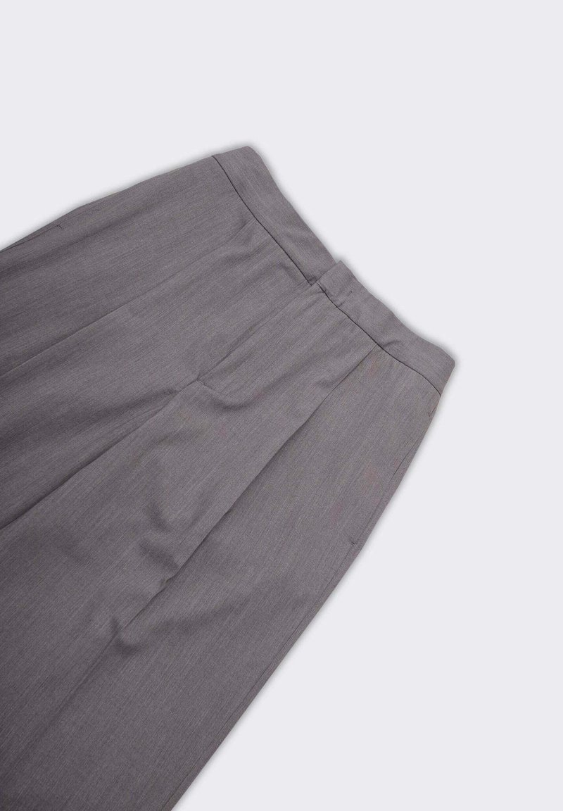 Pantaloni grigi su misura con una texture liscia, caratterizzati da un davanti piatto e pieghe. La vita è semplice e il tessuto ha una leggera lucentezza.
