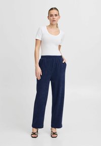 Hauts à manches courtes blancs et pantalon large marine en tissu texturé avec taille élastique, comportant des poches latérales et une coupe décontractée.