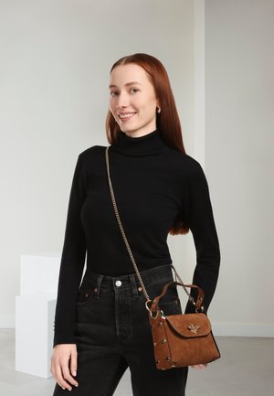 Bruine suède handtas met een kettingriem, bovenaan handvat en accenten in goudkleur. De tas heeft een klepsluiting en gespen met studs als decoratie.