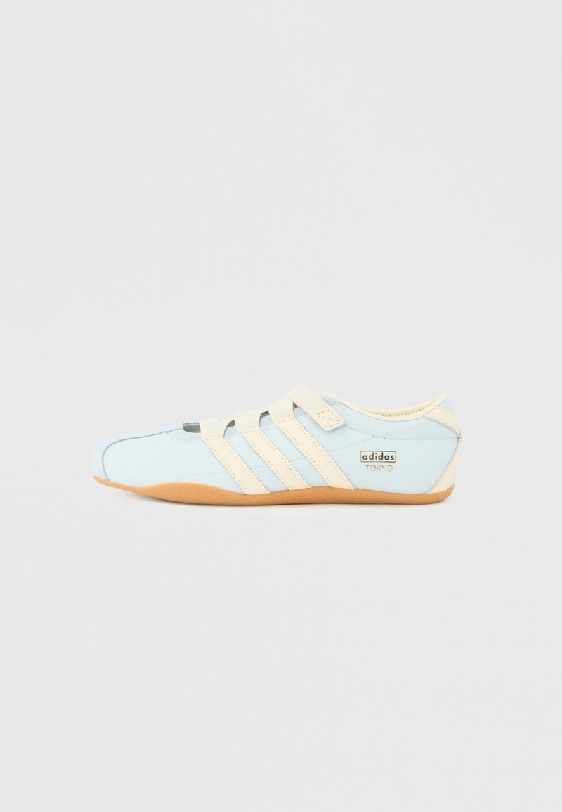 Baskets Adidas Tokyo bleu clair avec trois bandes beiges, sangles beiges et semelle en gomme sur un fond blanc uni.