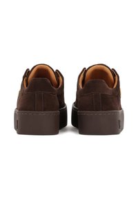 Tenisi din suede maro cu o talpă din cauciuc moale maro, având un finisaj texturat și detalii de cusătură subtile, văzuți din spate.