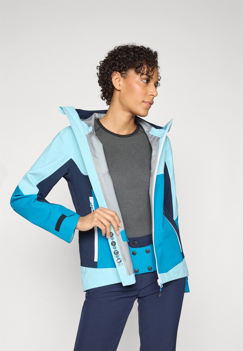 Hellblau und marineblau wasserdichte Jacke mit taillierter Passform, kontrastierenden Ärmeln und Reißverschluss vorne. Enthält Knöpfe und eine verstellbare Kapuze.