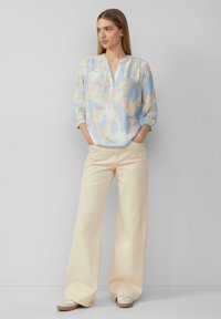 Lichtblauw met een patroon blouse met een V-hals, driekwartmouwen en ivoorkleurige wijde broek. De outfit heeft een ontspannen pasvorm en een zachte textuur.