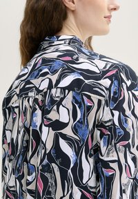 Langarmshirt met een zwart, wit en blauw abstract patroon. Lichtgewicht stof met een klassieke kraag en geplooid achterdetail.