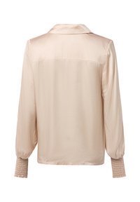 Pale beige satin blouse with long puffed sleeves, a collar, and smocked cuffs. Smooth texture, minimal stitching details on the back.
