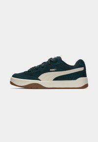 Puma sneakers in dark teal suede with beige accents, featuring a rounded toe, rubber sole, and classic lace-up design.