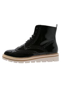 Botín de tobillo de charol negro con detalles de brogue, punta redondeada, suela de goma y un diseño de cordones que incluye una lengüeta en la parte posterior.