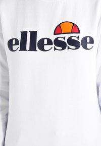 Sudadera blanca de manga larga con un gran logo negro de "ellesse" y un gráfico de mitades de esfera colorido en rojo, amarillo y naranja encima.
