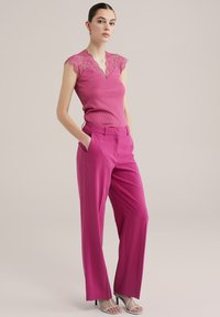 Top fucsia a coste con maniche a cappuccio in pizzo, abbinato a pantaloni fucsia a gamba larga. Presenta un design elegante e un tessuto leggero e morbido.