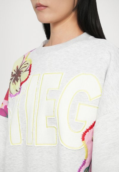Light gray sweatshirt with large yellow embroidered lettering. Features colorful floral appliqués on the sleeves, adding texture and detail.
