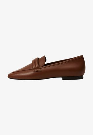 Mocassins en cuir marron avec un bout pointu, dotés d'une sangle décorative sur le devant et d'une semelle plate. Texture lisse, design minimaliste.
