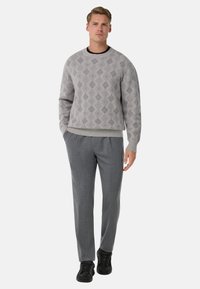 Pull gris clair avec motif en losanges, col rond et poignets côtelés, associé à un pantalon gris et des baskets noires.