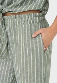 Lichte groene linnenmix broek met witte verticale strepen, elastische tailleband en zijzakken. Zachte textuur met een ontspannen pasvorm.