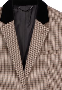 Hnědý a béžový sako s kostkovaným vzorem houndstooth, s černým sametovým límcem a hladkým vnitřním podšívkou s detailním řetízkem na krku.