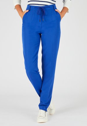 Blauwe op maat gemaakte broek met een trekkoord in de taille, zijzakken en een gladde textuur. In combinatie met witte sneakers voor een casual look.