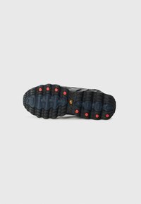 Svart atletisk skosole med texturerad gummi, synliga mönster för grepp och röda accenter. Har en distinkt båge och häldesign för stöd.