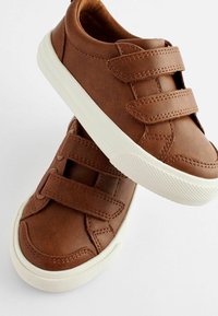 Chaussures en cuir synthétique marron avec deux bandes auto-agrippantes, semelles en caoutchouc blanches et semelle texturée pour une meilleure adhérence. Design à bout rond.
