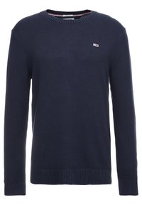 Granatowy sweter z dzianiny z okrągłym dekoltem, ściągaczami przy mankietach i u dołu, z małym logo na lewej piersi. Struktura jest gruba i ciepła.