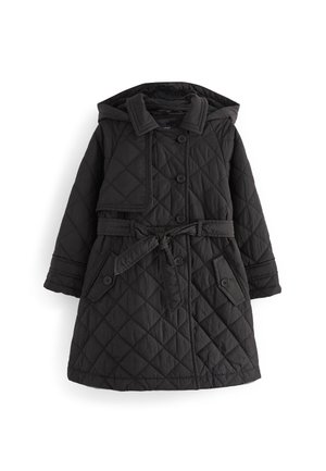 Manteau noir matelassé avec de gros boutons et une ceinture nouée à la taille, porté à l'extérieur lors d'une journée enneigée.