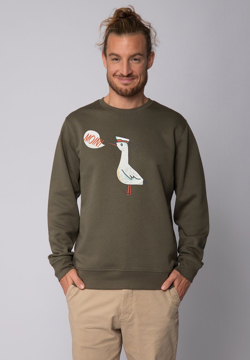 Olijfgroene sweatshirt van katoenmix, met een cartoonvogelontwerp en een oranje spreekwoord 'MOIN'. Geribde manchetten en zoom.