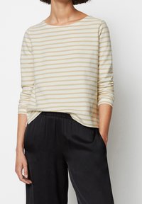 Gestreepte beige en witte shirt met lange mouwen van zachte stof, met een ronde halslijn en een losse pasvorm, gecombineerd met zwarte broek met elastische tailleband.