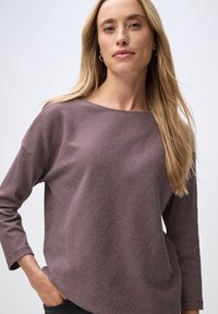 Maroon and cream striped long-sleeve top with a boat neckline and relaxed fit. Soft texture with side pockets; casual and versatile design.
