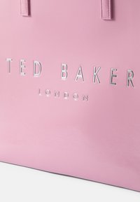 Saco tote sintético rosa com um acabamento texturizado, apresentando a inscrição em relevo a letras prateadas "TED BAKER LONDON" em destaque.
