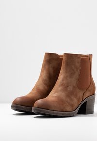 Brown suede ankle boots with a rounded toe, elastic side panels, textured accents, and a chunky heel. Smooth finish and sturdy base.