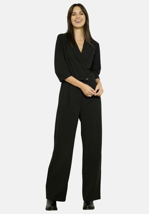 Zwarte, op maat gemaakte jumpsuit met een diepe V-hals, driekwart mouwen en wijde benen; heeft een enkele knoopsluiting.
