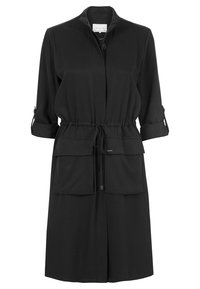 Abito giacca nero con collo a camicia, maniche arrotolabili, vita con coulisse e due tasche frontali. Tessuto liscio con una leggera lucentezza.