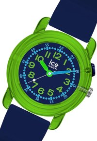 Montre en plastique verte avec un bracelet en caoutchouc bleu. Le cadran rond présente un fond bleu marine, de grands chiffres verts et des marqueurs d'heure bleus. Aiguilles à lecture instantanée.