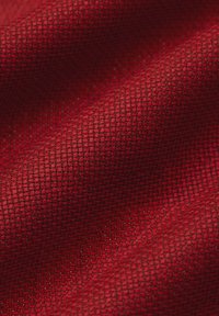 Czerwony tkany materiał o teksturowanej powierzchni, z ciasnym, siatkowym wzorem i gładkim, lekko błyszczącym wykończeniem.