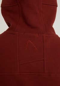 Sudadera de color rojo oscuro exhibida desde la parte de atrás, con detalles de costura y un pequeño diseño bordado apuntando hacia arriba cerca del cuello.